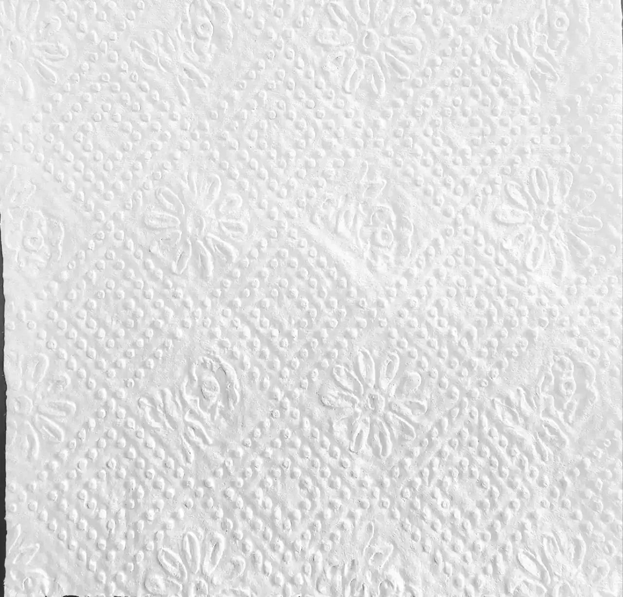 Close-up of embossed white bathroom tissue with floral and dotted pattern, ultra-soft texture